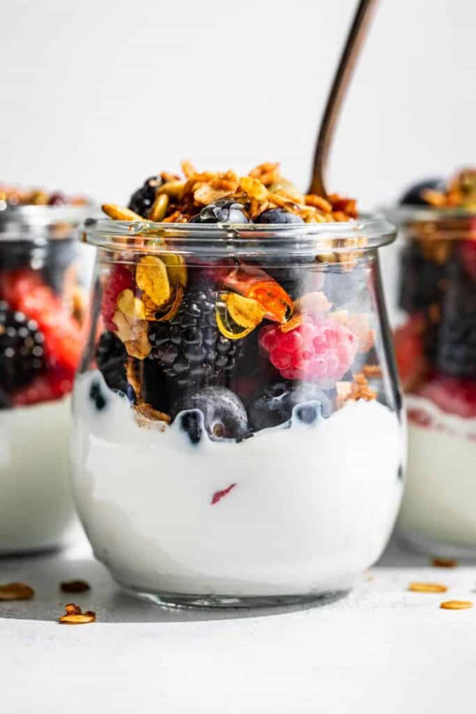 Glass jar with berries & granola yogurt parfait.