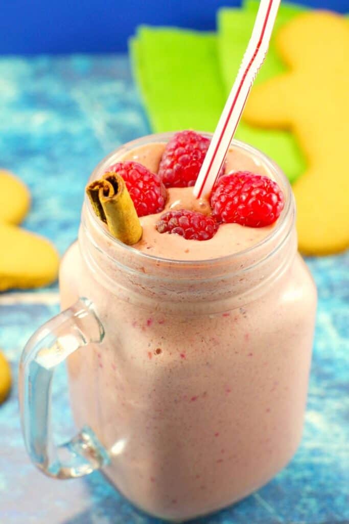 Glass mug of gingerbread smoothie with raspberries on top.