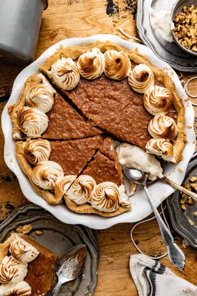 Old fashioned sweet potato pie in a ceramic scalloped pan with one slice missing.