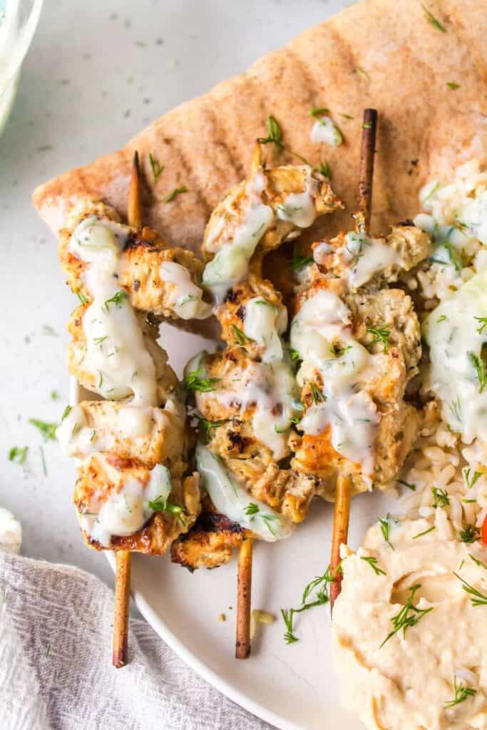 Wooden skewers with grilled chicken and greek sauce on a pita. 