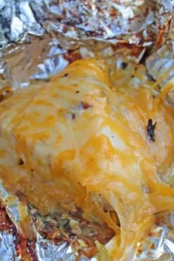 Chicken breast covered in green chilis and cheese in tinfoil. 