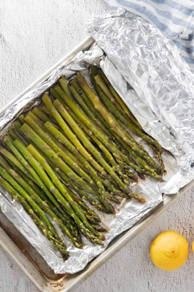 An overhead view of a pan of foil packet grilled asparagus with lemon. 