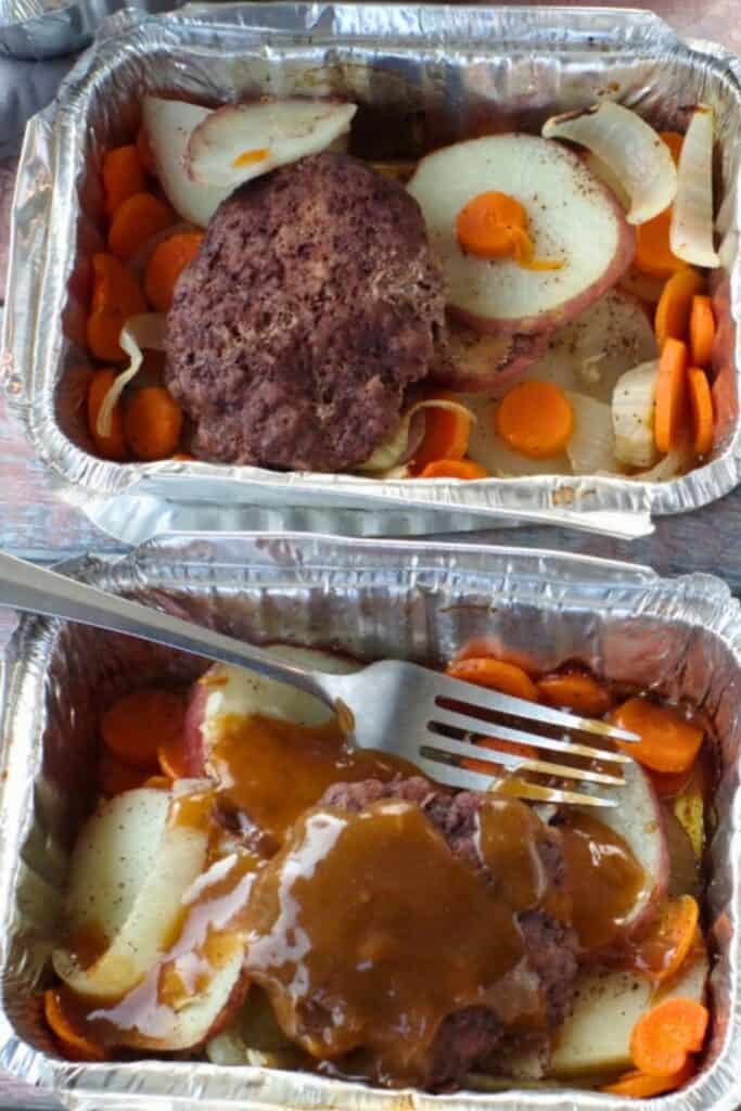 Two tinfoil pans with a hamburger patty, and sliced carrots and red potatoes inside.