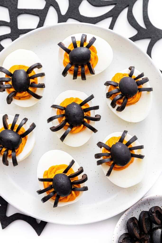 Plate of Halloween devilied eggs with black olive spiders on top. 