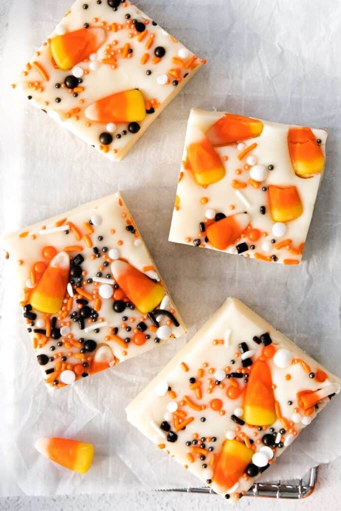 Squares of Halloween Fudge decorated with Halloween colored sprinkles and candy corn. 