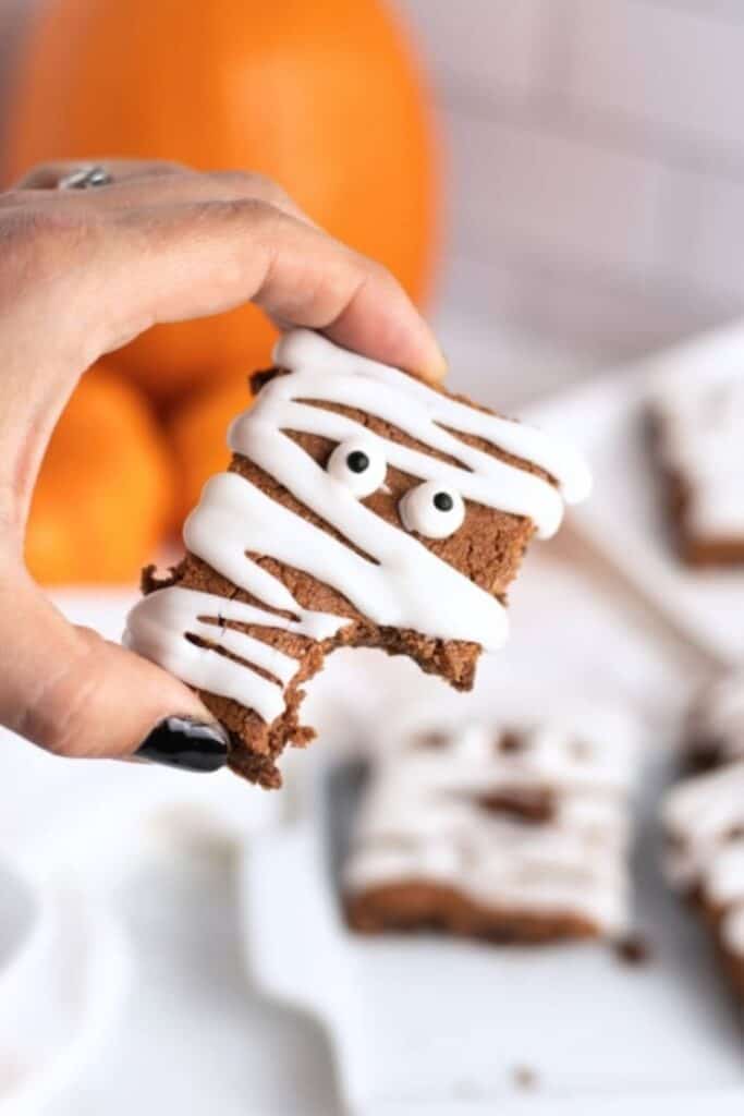 Hand holding a mummy brownie with candy eyes.
