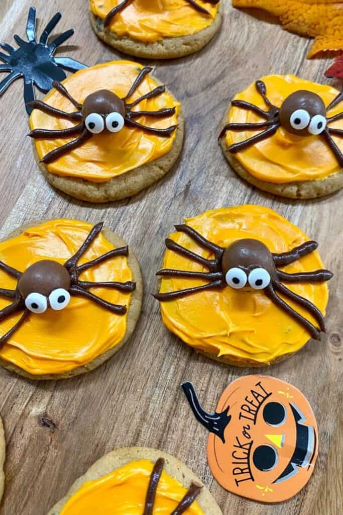 Round flat cookies with a round chocolate candy spider and orange icing. 