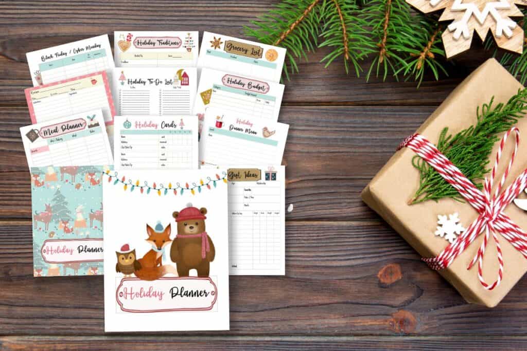 12 printable pages of the Holiday planner woodland animal theme spred out over a dark wooden background, and paper wrapped prest and tree boughs.