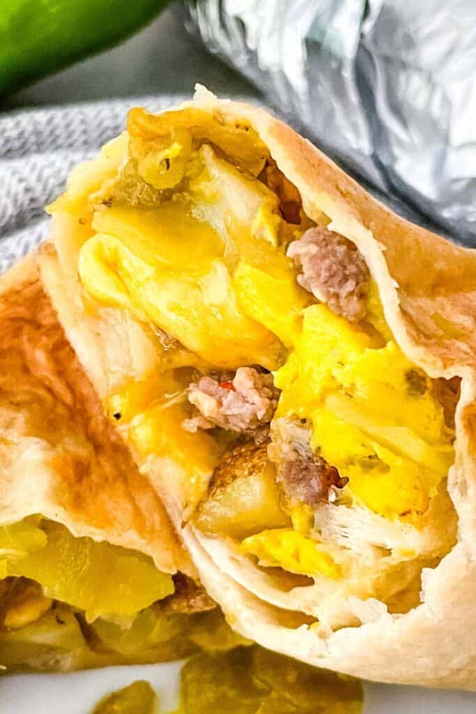 Up close look at a breakfast burrito with egg, cheese, ground pork wrapped in a tortilla