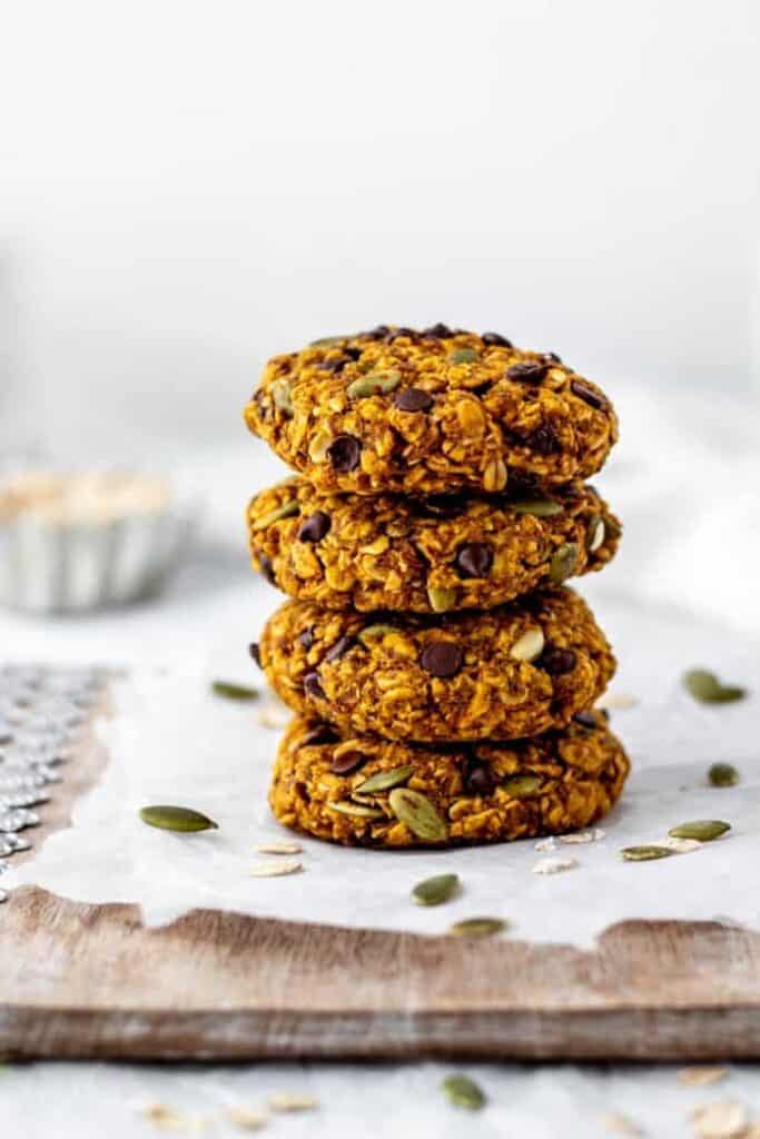 Stack of 4 healthy pumpkin chocolate chip cookies on a piece of parchemnt paper. 