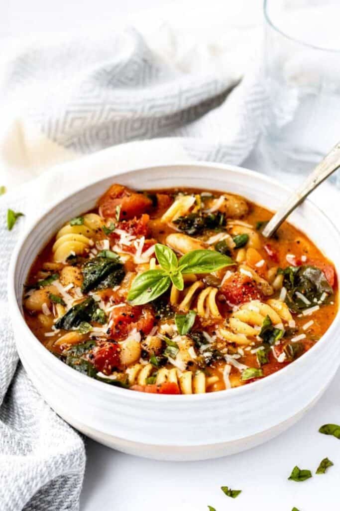 Bowl of white bean, rotini and spinach soup. 