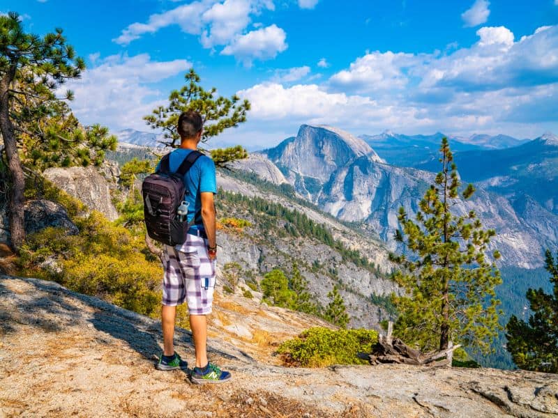 Young man hiking in Yosemite looking towards half dome.