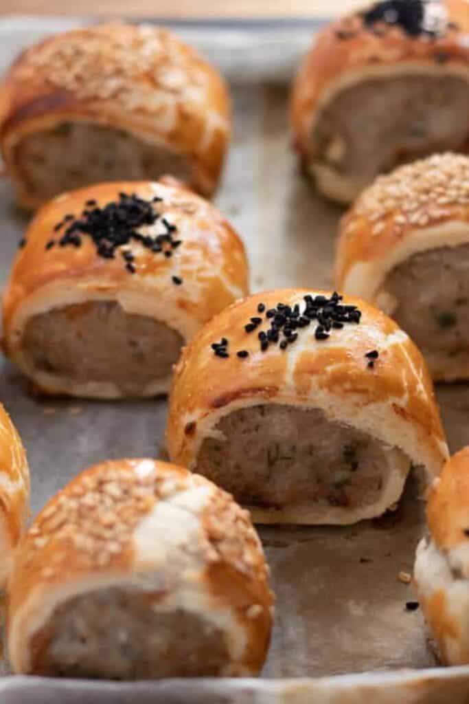 Close up of mini sausage rolls on a baking sheet, for Christmas finger foods. 