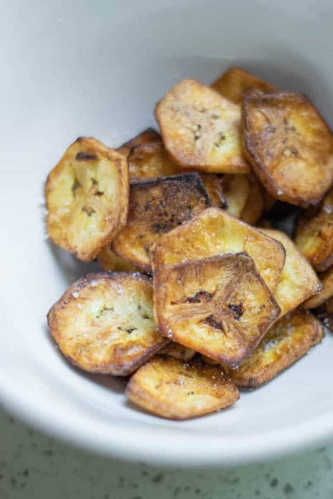 An overhead view of a bowl of homemade banana chips for road trip snacks. 