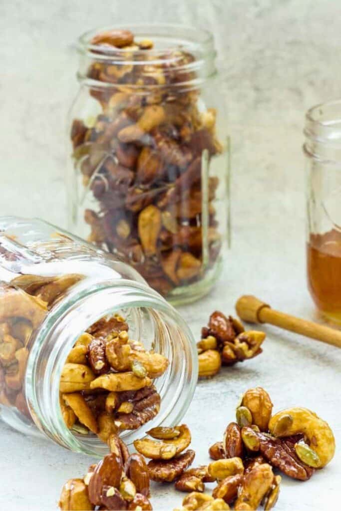 Class mason jars filled with honey nut clusters, one on it's side with the contents falling out.  