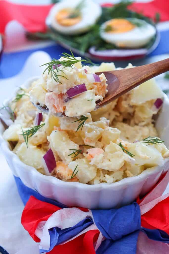 Close up of a wooden spoon with a scoop of homemade potato salad with mayo dressing.