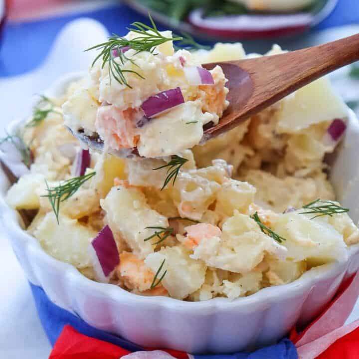 Close up of a wooden spoon with a scoop of homemade potato salad with mayo dressing.