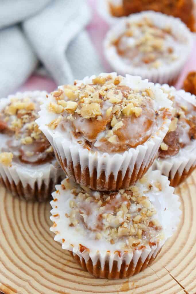 Close up of 3 piled moist pumpkin muffins with icing and walnuts on top.