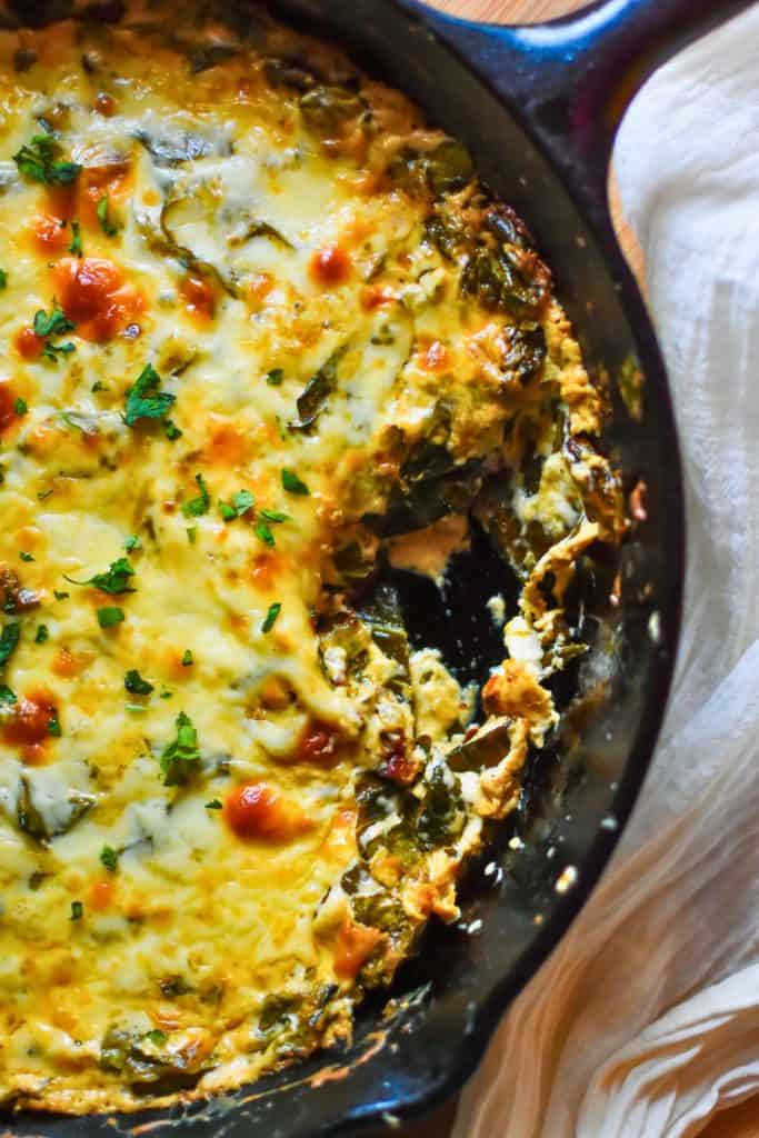Bubbly Hot Collard Greens Dip baked in a cast iron skillet, topped with melted golden cheese, hot sauce, and fresh parsley. A rich, creamy appetizer with Southern flavors perfect for game day or parties.
