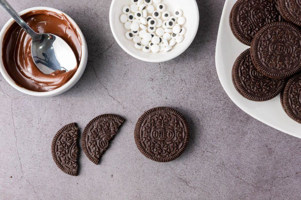 Making the oreo bat wings. A whole oreo beside half an oreo split into two. 