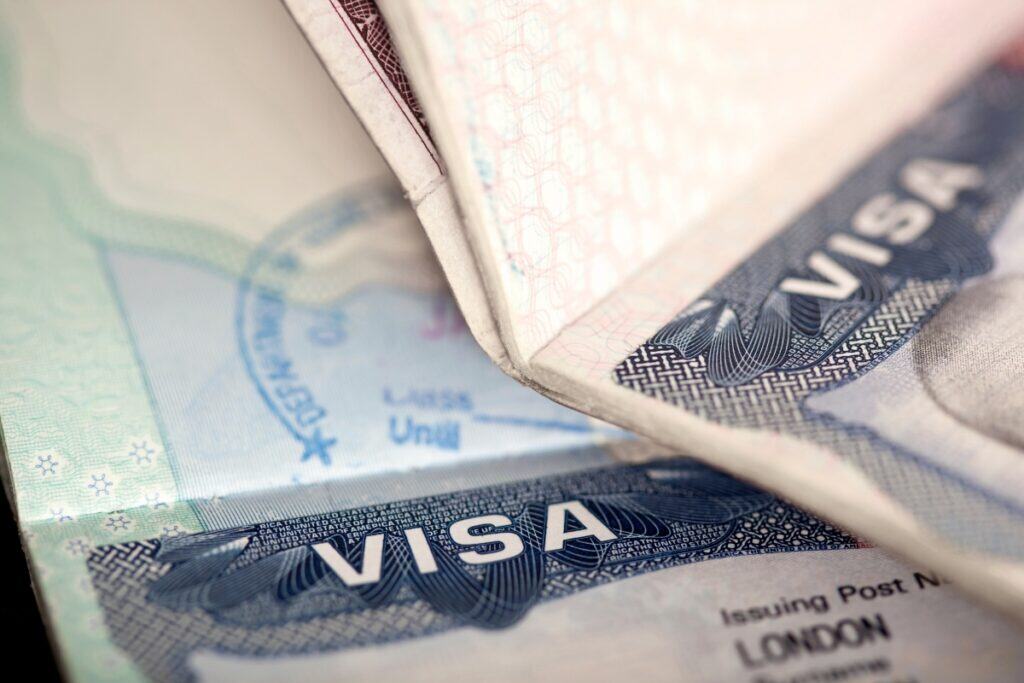 Close up of a passport open to a visa page with a visible visa stamp and the word Visa prominently displayed. The image represents important travel documents to copy and store securely before an international trip.