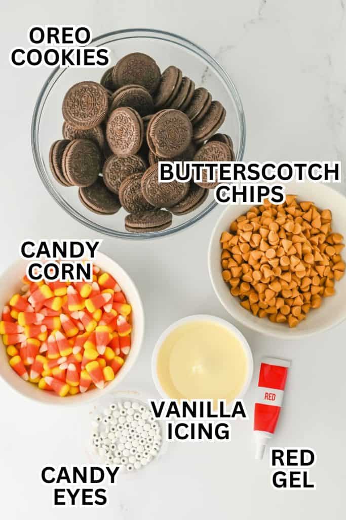 Top-down view of ingredients for no bake Thanksgiving treats, including Oreo cookies, butterscotch chips, candy corn, candy eyes, vanilla icing, and a tube of red gel. Each item is labeled and arranged on a white surface, ready for assembling turkey-themed cookies.