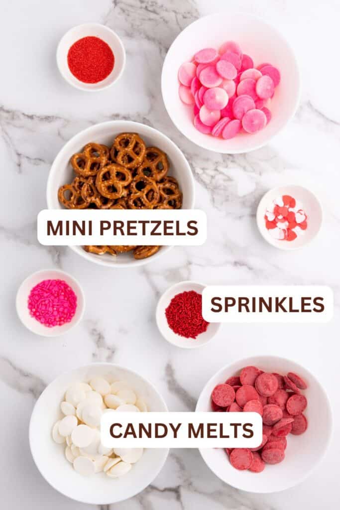 Ingredients for Valentine's pretzels in small bowls. Includes red, white & pink candy melts, sprinkles and mini pretzels.