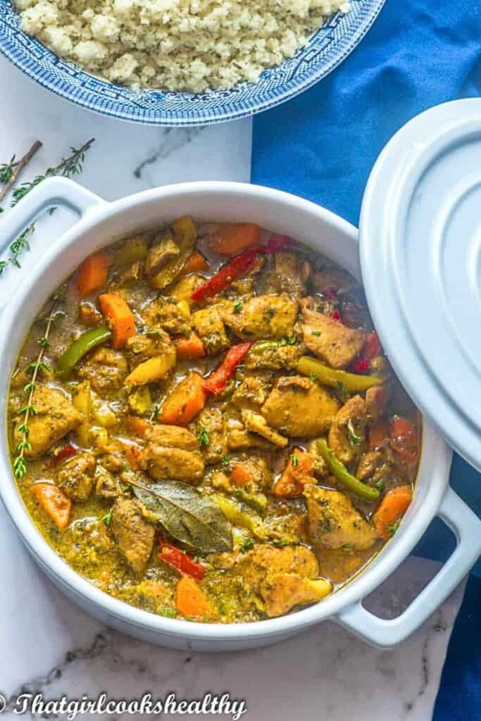 Slow cooker Jamaican Coconut Curry Chicken and peppers in a round ceramic pot.