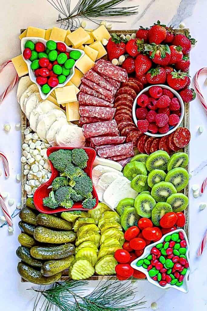 Kids Christmas Charcuterie board with deli meats, cheese, pickles, kiwis, raspberries, M&Ms.