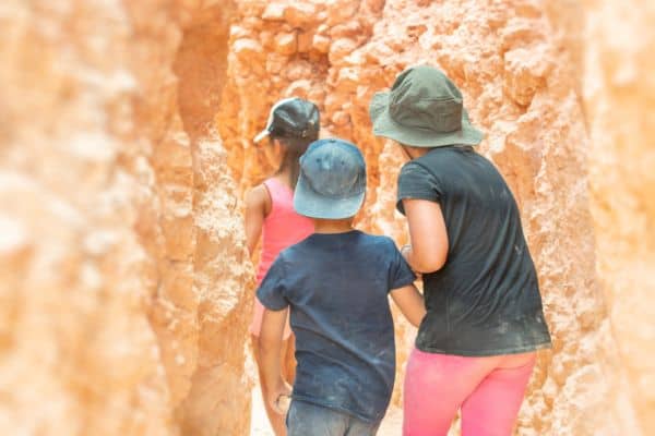 3 Kids in ball caps hiking through red rocks in Zion.