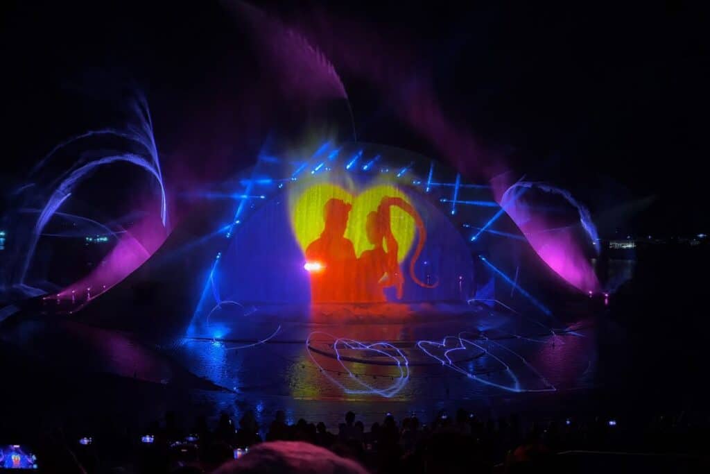 A stage showing a multimedia show with lights projecting two figures on a screen. 