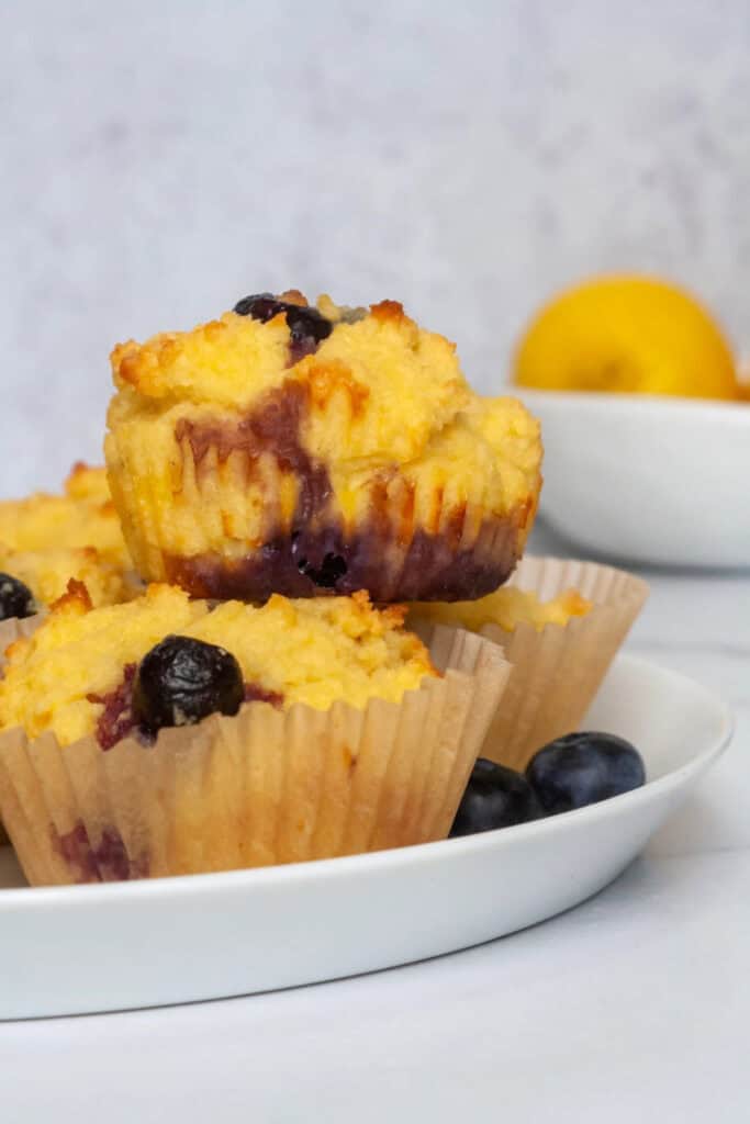 Four lemon blueberry muffins piled on a plate. 