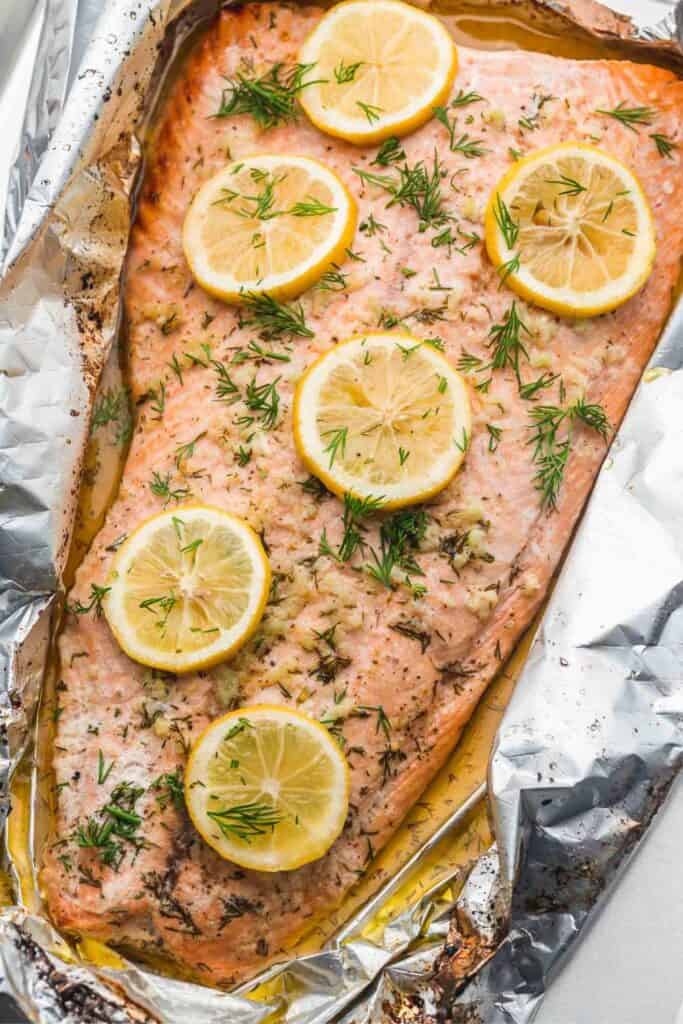 Baked salmon in tinfoil topped with lemon slices and fresh dill.