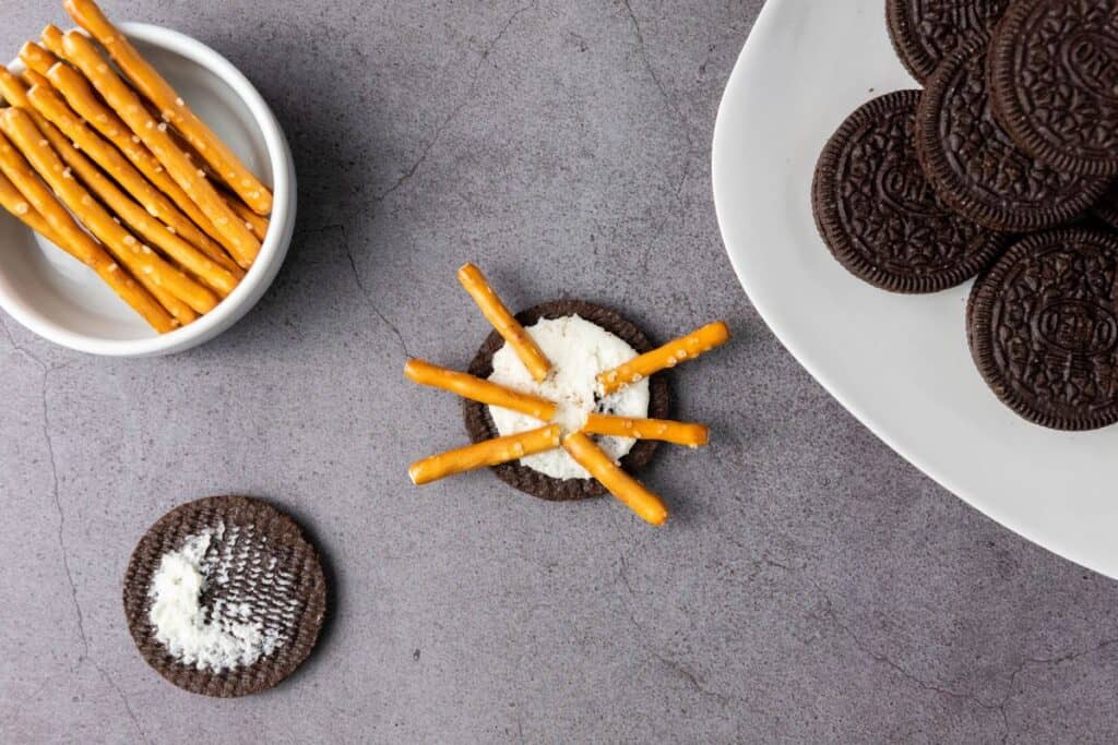 Oreo cookie opened up, with pretzel legs on top of the icing. 