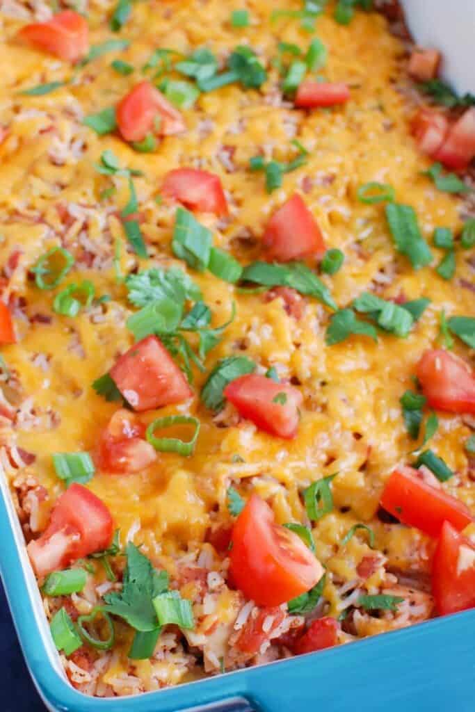 Rectangle mexican rice chicken casserole topped with tomatoes and parsley. 