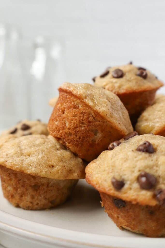 Pile of mini banana chocolate chip muffins on a plate. 