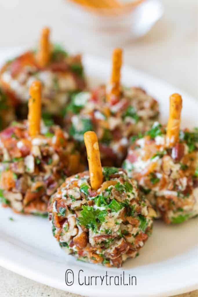 Close up of bacon, creamcheese mini cheese balls with pretzel sticks to help pick them up. 