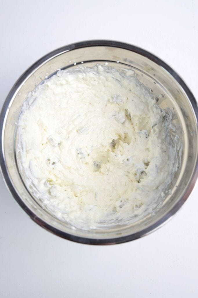 Overhead view of a metal bowl filled with a creamy mix of cream cheese and sour cream.