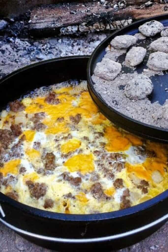 Sausage, egg, cheese breakfast csserole in a cast-iron Dutch Oven over coals.