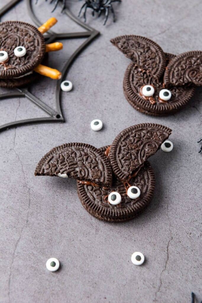 Two oreo bats with candy eyes on a dark background.