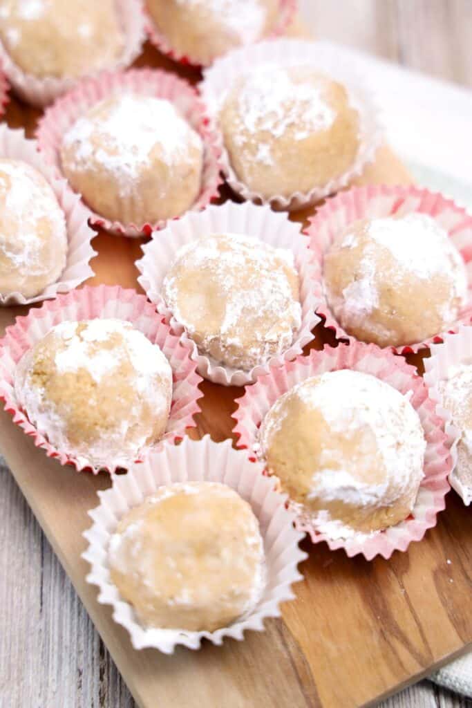 Nine powdered sugar covered no bake peanut butter snack balls in mini cupcake liners. 