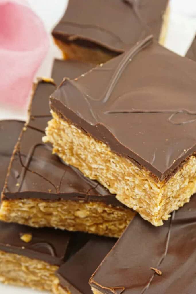 Close up of squares of peanut butter oat bars covered in chocolate. 