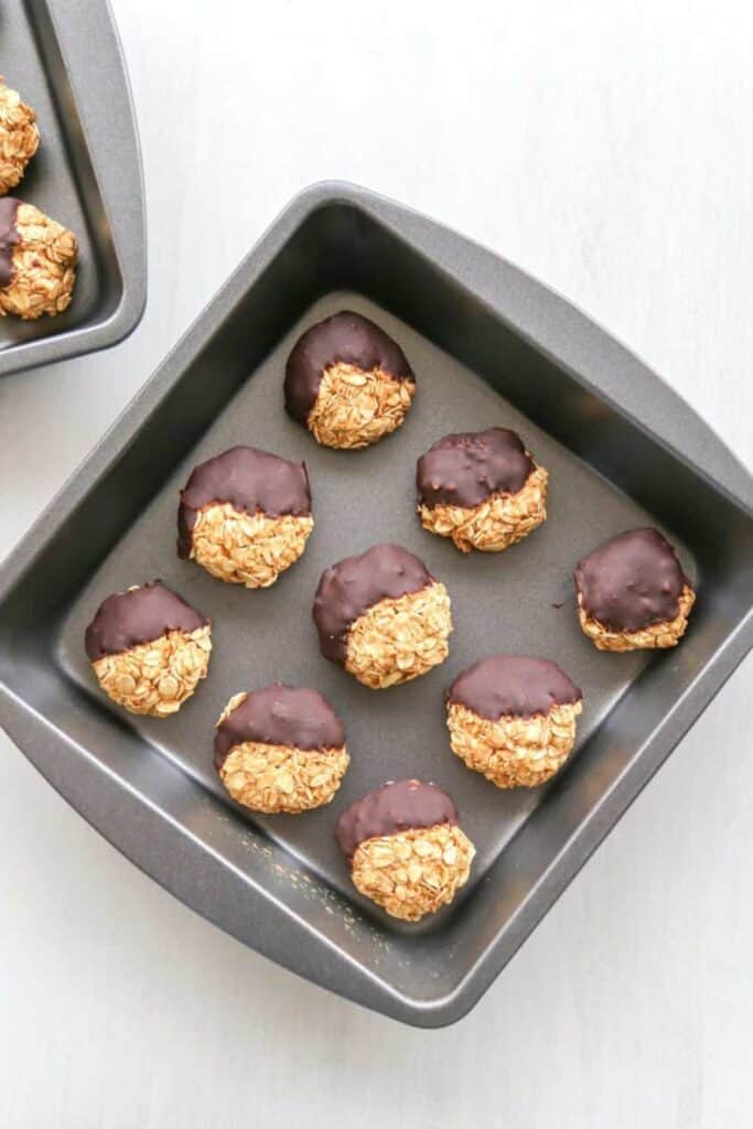 Tray of nine no bake oatmeal pumpkin cookies half dipped in chocolate. 