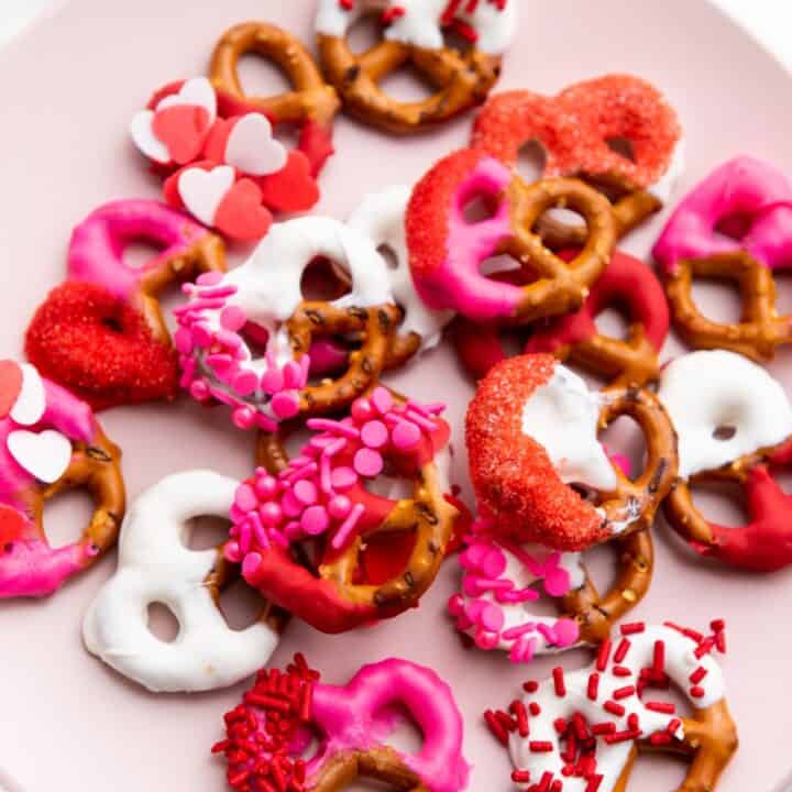 Overhead view of a plate of Valentine's themed dipped pretzels with sprinkles.