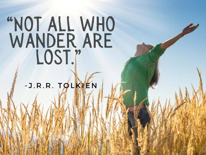 Woman with arms flung in the air, head tilted back facing the sun while standing in a field of tall grass. Quote: " Not all who wander are lost."