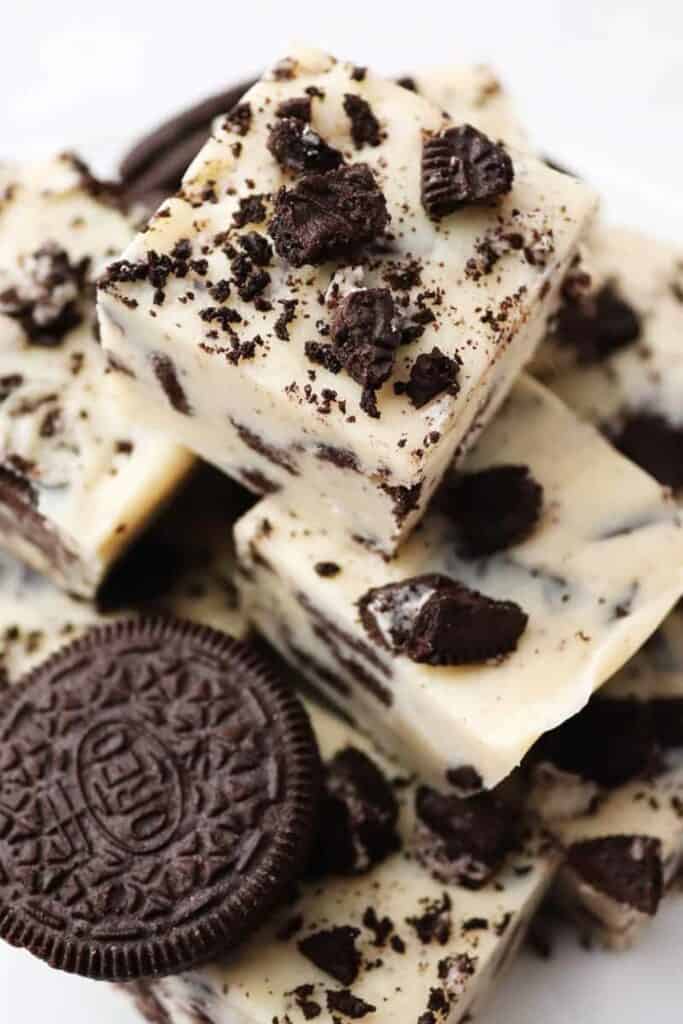 Close-up of homemade Oreo fudge made with creamy white chocolate and chunks of crushed Oreo cookies, stacked in a tempting pile.