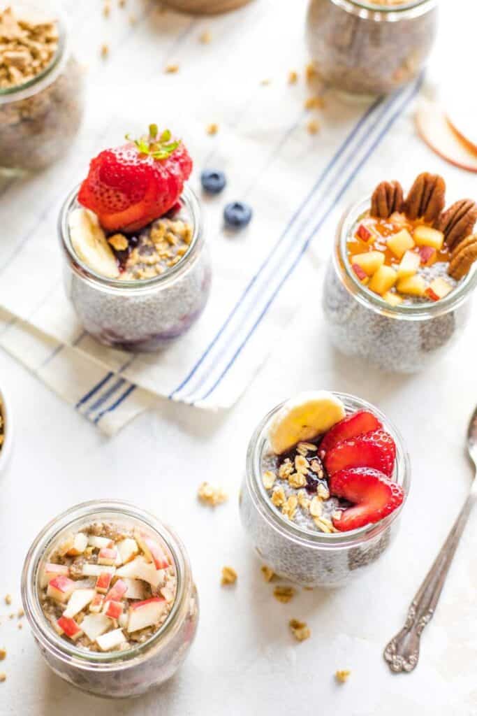 Four jars of overnight chia pudding with different fruit & nut toppings. 