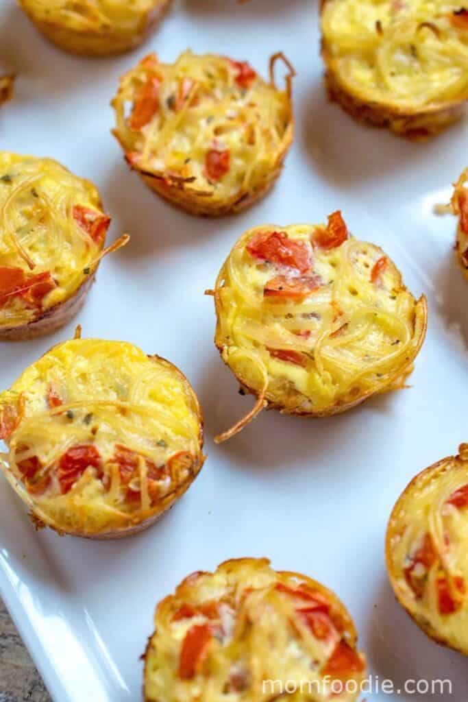 Alt text: Pasta frittata muffins made with spaghetti eggs and diced tomatoes baked into small bite sized cups with lightly crisp edges.