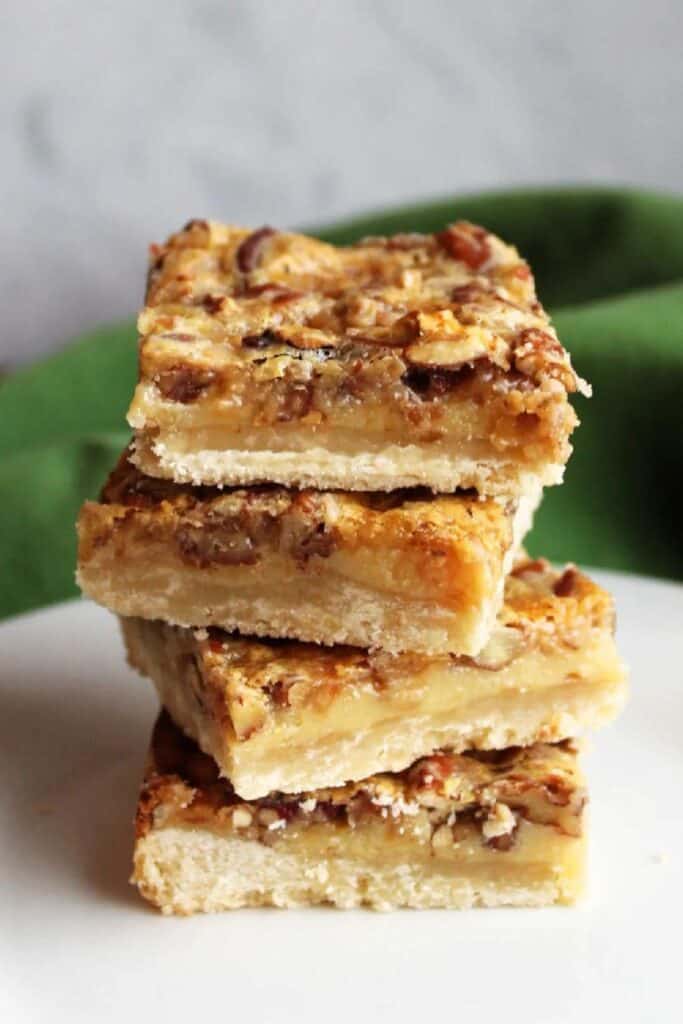 Close up of a Stack of four pecan pie pars with shortbread crust. 