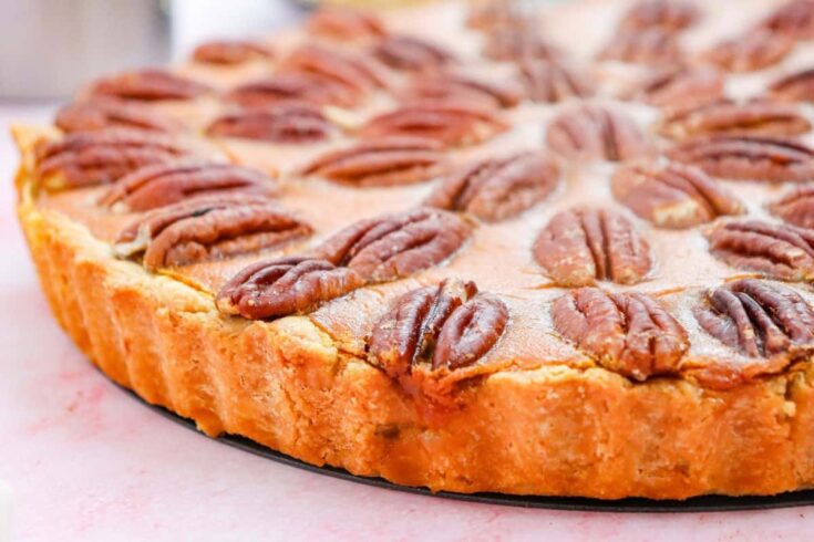 Close up of the whole pecan pumpkin cheesecake with scalloped edges